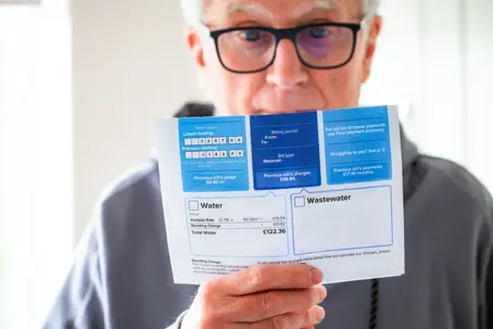 a senior man in his 70s checking his water bill at home